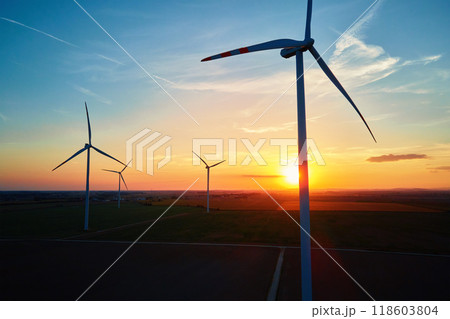 Silhouetted wind turbines in countryside landscape during sunset. Wind power plant generating clean energy. Concept of renewable and sustainable energy 118603804