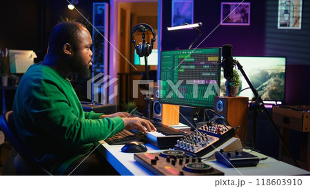 Producer composing new track with electronic gear in his home studio, creating music on mixing console and software interface. Talented artist songwriter controls panel to produce sounds. Camera B. Producer composing new track with electronic gear in his home studio, creating music on mixing console and software interface. Talented artist songwriter controls panel to produce sounds. Camera B. 118603910
