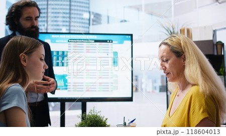 Financial advisor meeting with customers to counsel them on their finances, offering them strategy to achieve futureproof income. Economy expert giving budget management tips, camera A Financial advisor meeting with customers to counsel them on their finances, offering them strategy to achieve futureproof income. Economy expert giving budget management tips, camera A 118604013