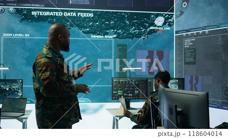 Military team operating in a high tech command post control tower, focusing on surveillance tactics for intelligence gathering. Data protection to manage critical information operations. Camera B. Military team operating in a high tech command post control tower, focusing on surveillance tactics for intelligence gathering. Data protection to manage critical information operations. Camera B. 118604014