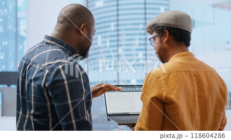 Corporate clients evaluating an investment opportunity in real estate, reviewing architectural blueprints and discussing the best strategies for office relocation and creative development. Camera B. 118604286