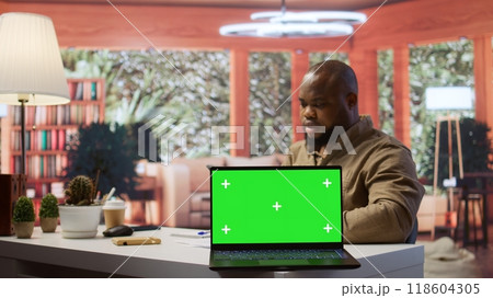 Young entrepreneur reviewing budget balance reports at his home desk, using mockup copy space display on a tablet. Businessman reviews monthly sales to obtain new investment funds. Camera B. 118604305