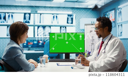 General practitioner consulting a female patient next to isolated chroma key display, sharing insight on lab test results and analysis. Skilled medic supports his client, indoors check up. Camera B. General practitioner consulting a female patient next to isolated chroma key display, sharing insight on lab test results and analysis. Skilled medic supports his client, indoors check up. Camera B. 118604311