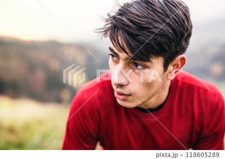 Portrait of male runner resting after jog in nature, enjoying view on autumn landscape. Morning running training for young man. Portrait of male runner resting after jog in nature, enjoying view on autumn landscape. Morning running training for young man. 118605289