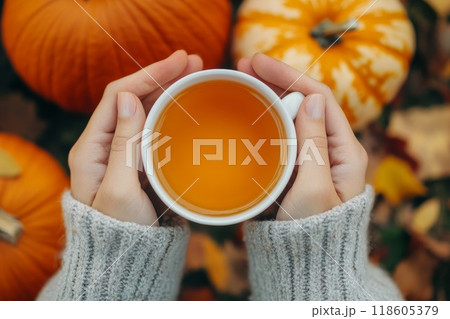 Hands holding cup of tea and pumpkin. Generative AI. Hands holding cup of tea and pumpkin. Generative AI. 118605379