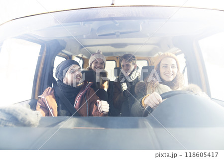 Friends traveling by car on winter holiday, spending Christmas in cabin. Driving through snowy landscape. 118605417