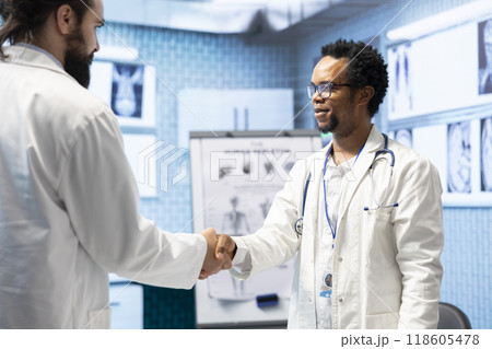 Diverse medics shaking hands after a successful treatment plan collaboration during a meeting with licensed physicians. Doctors with expertise doing a handshake for great partnership in office. Diverse medics shaking hands after a successful treatment plan collaboration during a meeting with licensed physicians. Doctors with expertise doing a handshake for great partnership in office. 118605478