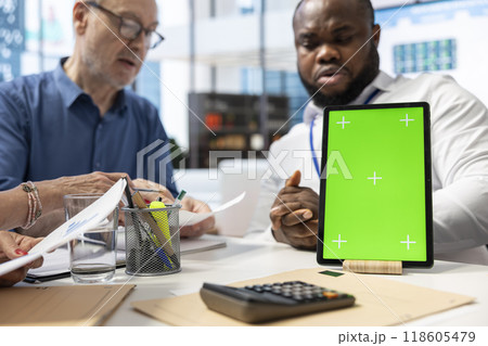 Financial advisor and clients exploring pension plans options next to green screen, pointing at tablet during counseling meeting. Broker assisting senior people about investment. Financial advisor and clients exploring pension plans options next to green screen, pointing at tablet during counseling meeting. Broker assisting senior people about investment. 118605479