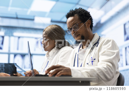 Medics in a private clinic examining test results and x ray scans during meeting, professionals discuss treatment plans and disease prevention strategies. Collective work ensuring quality healthcare. 118605593