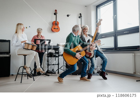Group of seniors meeting to play musical instruments together in band, having fun. Therapeutic effect of music for elderly people. 118606175