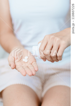 woman hand holding medicine painkiller pill on the sofa at home, taking for headaches, stomach ache, Diarrhea Pain from food poisoning, Endometriosis, Hysterectomy and Menstrual woman hand holding medicine painkiller pill on the sofa at home, taking for headaches, stomach ache, Diarrhea Pain from food poisoning, Endometriosis, Hysterectomy and Menstrual 118607226
