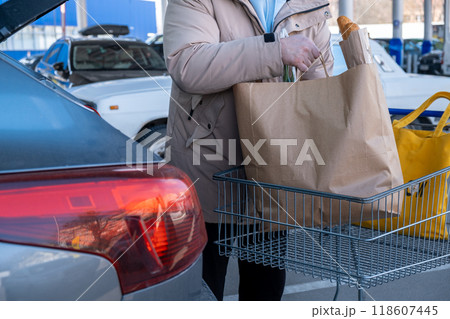 Man Loading Groceries into Car Trunk Man Loading Groceries into Car Trunk 118607445