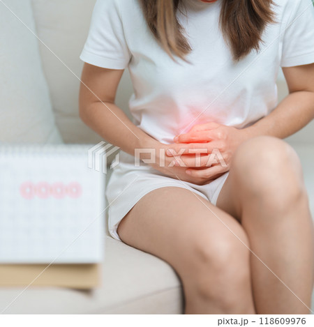 Menstruation period cycle of monthly and Stomachache concepts. woman having abdomen pain with calendar, illness female suffer from premenstrual ache and body Health problem on sofa at home 118609976