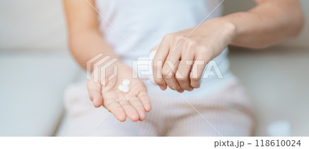 woman hand holding medicine painkiller pill on the sofa at home, taking for headaches, stomach ache, Diarrhea Pain from food poisoning, Endometriosis, Hysterectomy and Menstrual woman hand holding medicine painkiller pill on the sofa at home, taking for headaches, stomach ache, Diarrhea Pain from food poisoning, Endometriosis, Hysterectomy and Menstrual 118610024