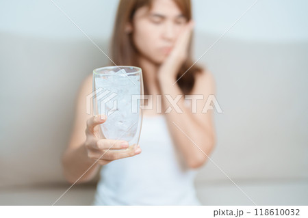 Teeth Sensitive to Cold concept. woman hold Ice Water glass and having toothache and pain after eat. Tooth Decay or Gum Disease, Grinding Teeth and Stress, Exposed Nerve Roots, Crack and Receding Gums 118610032