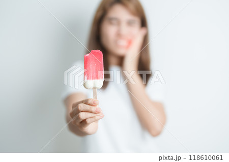 Teeth Sensitive to Cold concept. woman hold Ice cream and having toothache and pain after eat. Tooth Decay or Gum Disease, Grinding Teeth and Stress, Exposed Nerve Roots, Crack and Receding Gums Teeth Sensitive to Cold concept. woman hold Ice cream and having toothache and pain after eat. Tooth Decay or Gum Disease, Grinding Teeth and Stress, Exposed Nerve Roots, Crack and Receding Gums 118610061