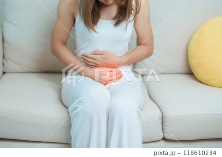 woman having abdomen ache due to Stomach pain, digestion with constipation or Diarrhea from food poisoning, female problem and Endometriosis, Hysterectomy, Stomachache and Menstrual on sofa at home 118610234