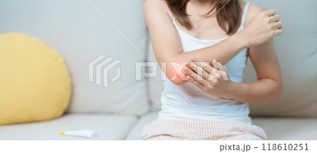 Arthritis and Muscle Pain Relief Cream concept. Woman having elbow ache at home, muscle pain due to lateral epicondylitis or tennis elbow. injury, Health and medical concept 118610251