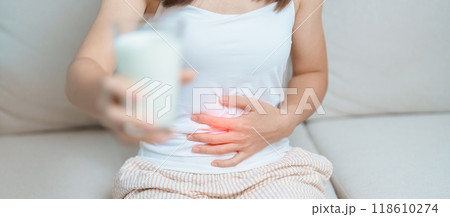 Lactose intolerance and Milk allergy concept. woman hold Milk glass and having abdominal cramps and pain when drink Cow Milk. Symptom stomach ache, Dairy intolerant, Nausea, Bloating, Gas and Diarrhea 118610274