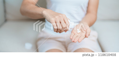 woman hand holding medicine painkiller pill on the sofa at home, taking for headaches, stomach ache, Diarrhea Pain from food poisoning, Endometriosis, Hysterectomy and Menstrual woman hand holding medicine painkiller pill on the sofa at home, taking for headaches, stomach ache, Diarrhea Pain from food poisoning, Endometriosis, Hysterectomy and Menstrual 118610408