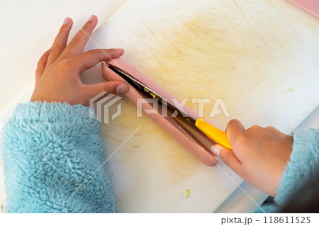 こども包丁で魚肉ソーセージを切る10歳の男の子の手元 118611525