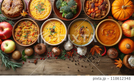 The Harvest Bounty Feast. A rustic wooden table laden with an array of autumnal dishes, showcasing the season's bounty: roasted root vegetables, creamy pumpkin soup, and hearty apple crumble. 118612348