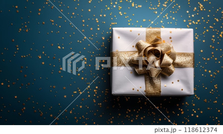 Happy birthday. Photo of a white gift box with gold ribbon on a blue background, surrounded by small golden stars for Christmas and New Year celebration. Web banner with copy space Happy birthday. Photo of a white gift box with gold ribbon on a blue background, surrounded by small golden stars for Christmas and New Year celebration. Web banner with copy space 118612374