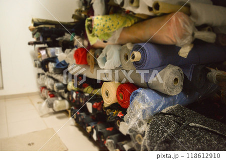 A vibrant stack of multi-colored fabric rolls, arranged in diverse palette. Perfect for sewing, crafting, and design projects. Fashion designers, tailors, and textile materials 118612910