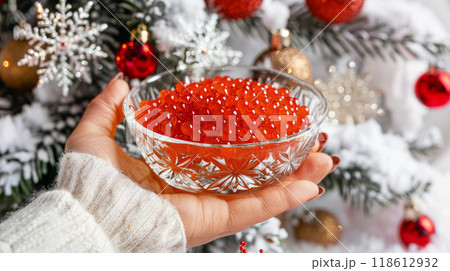Glass Bowl of Red Caviar Held Against Festive Background 118612932