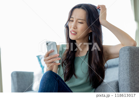 ソファでスマホを見る女性　ネガティブ 118613017