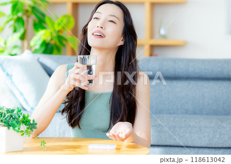 リビングでサプリを飲む若い女性 118613042