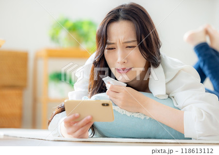 リビングで寝転がりながらスマホを見る女性 リビングで寝転がりながらスマホを見る女性 118613112