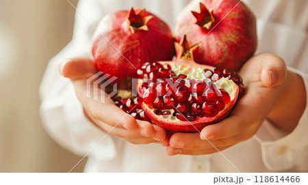 Fresh pomegranates and seeds held in hands highlighting natural abundance and vibrant color 118614466