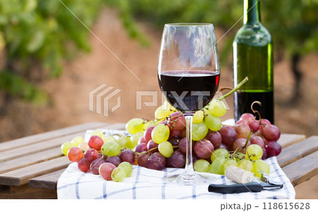 Glass of red wine and ripe grapes on table 118615628