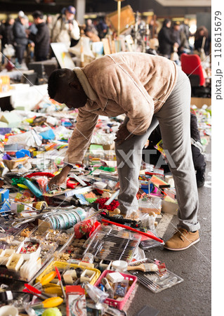 man looks at second-hand items at a flea market man looks at second-hand items at a flea market 118615679
