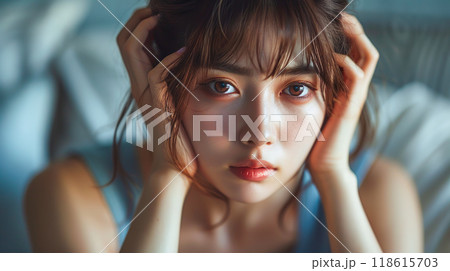 部屋で頭を抱える若い女性 118615703