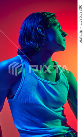 Portrait in blue neon light of young attractive man with long hair dressed casual outfit against gradient studio background. 118615800