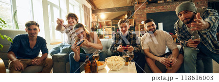 Banner. Snacks on table, drinks in hand, and the match on. Excitement builds as friends dive deeper into virtual world, connected by fun. 118616003