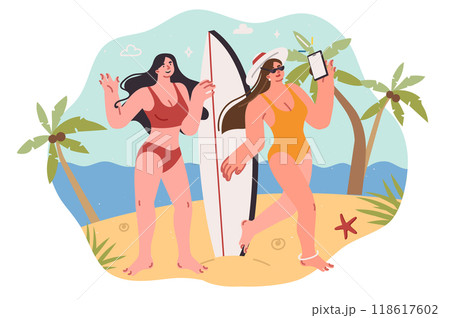 Two woman surfers take selfie on phone, standing on beach and posing with surfboard in hands 118617602