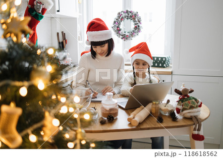 Mother and daughter baking cookies on Christmas in cozy kitchen 118618562