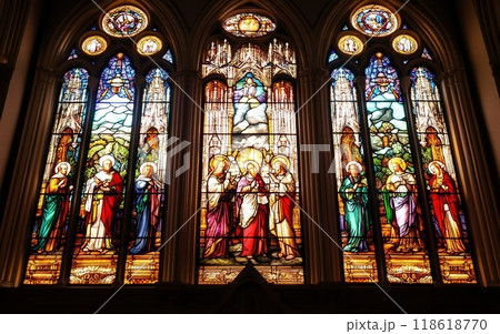 Elaborate stained glass windows in a cathedral, featuring detailed portrayals of biblical figures and religious scenes, framed by Gothic arches 118618770