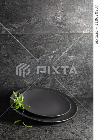 Empty round black plates with rosemary on a black stone background. Empty round black plates with rosemary on a black stone background. 118620837