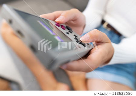 Close-up of female hands of young Caucasian woman holding retro video game console. Girl playing retro games on portable game console. Shallow depth of field. Selective focus 118622580