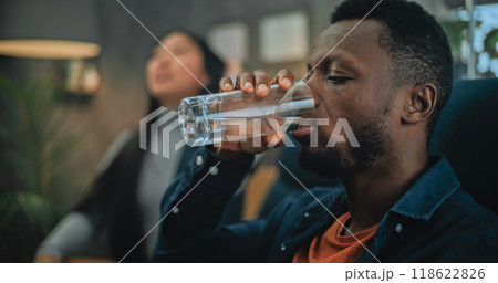 Close up of annoyed African American man drinking water during couples therapy 118622826