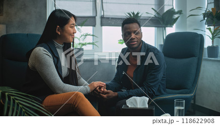 Happy multiethnic couple sit on chairs holding hands after quarrel on couples therapy 118622908