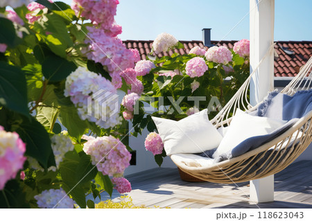 Outdoor roof terrace with hammock and potted blooming hydrangea overlooking the sky and roofs 118623043