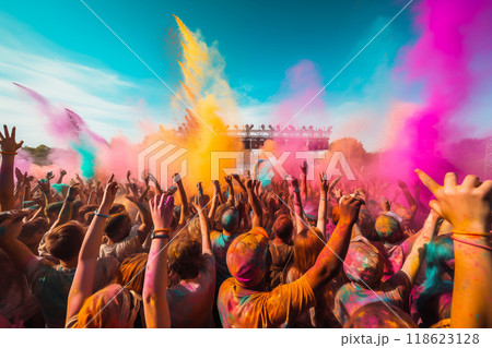 Crowd celebrating with vibrant color powder at a festival under a sunny sky 118623128