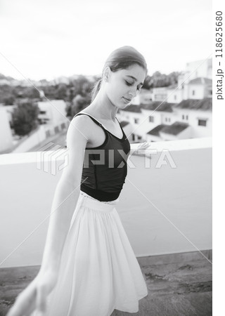 An Elegant Ballerina Posing Gracefully on a Rooftop Against a Beautiful Cityscape Background An Elegant Ballerina Posing Gracefully on a Rooftop Against a Beautiful Cityscape Background 118625680