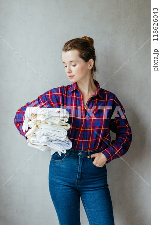 European woman holds lot of colored clothes hands for laundry or recycling. European woman holds lot of colored clothes hands for laundry or recycling. 118626043