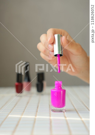 pink nail polish with bottle and brush. woman paints her nails and gets a manicure. 118626052